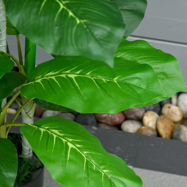 Künstliche Pflanze mit großen grünen Blättern und hellen Blattadern in der Detailansicht.