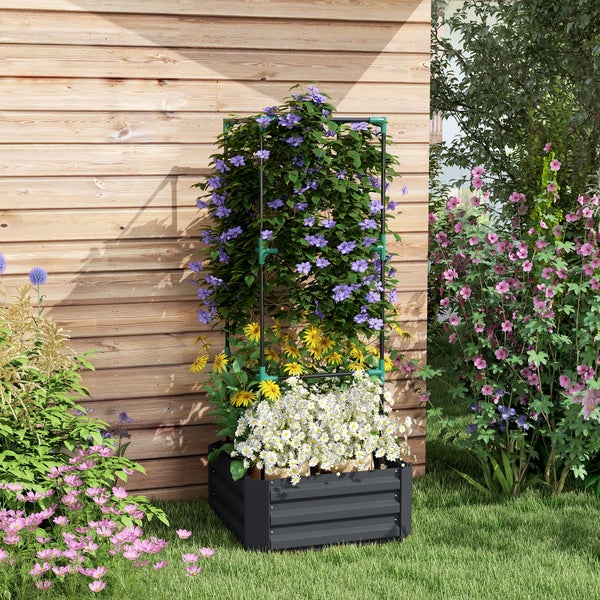Anthrazitfarbenes Hochbeet mit Rankhilfe vor einer Holzwand, bepflanzt mit weißen, gelben und violetten Blumen im sonnigen Garten.