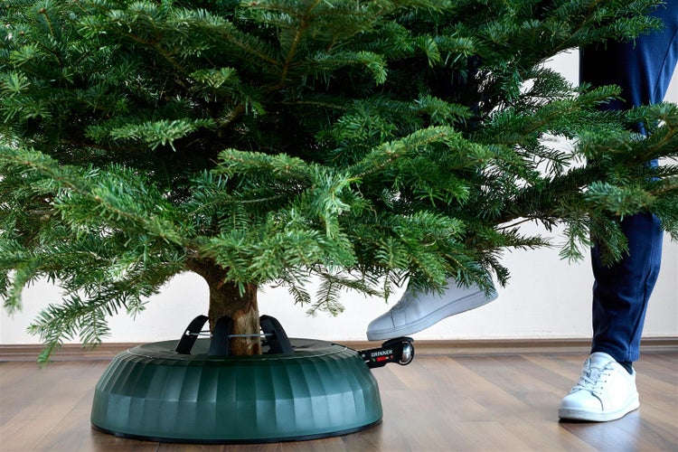 Weihnachtsbaum im Christbaumständer mit Fußbedienung auf Holzboden