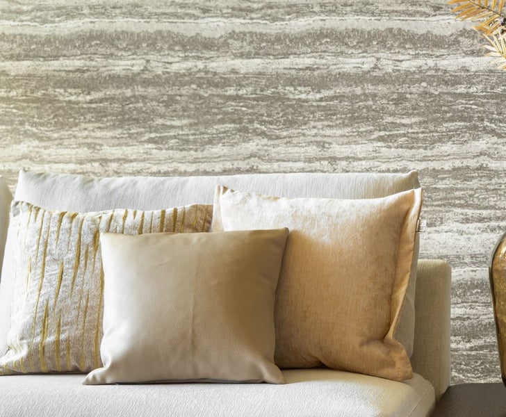 Dekorative Kissen auf einem Sofa vor einer Wand mit Muster