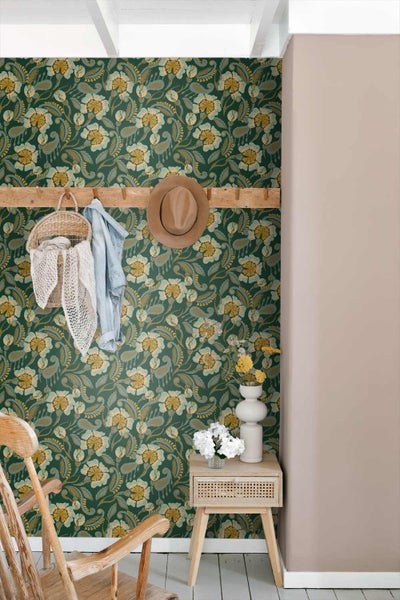 Vliestapete mit floralem Muster in einem Raum mit Holzgarderobe, Hut und Nachttisch aus Holz.