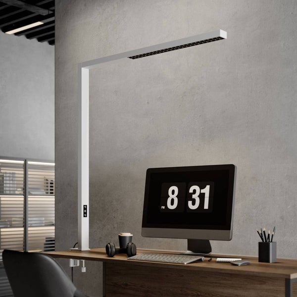 Moderne weiße LED-Schreibtischlampe mit Klemmfuß, montiert an einem Holztisch in einem minimalistischen Arbeitszimmer mit Computer.