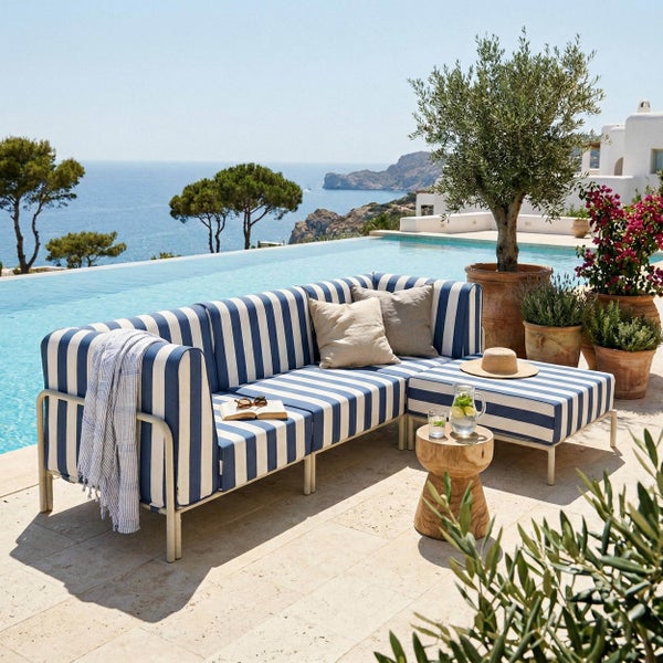 Modulares Outdoor-Sofa mit gestreiften Kissen auf einer hellen Terrasse an einem Infinity-Pool mit Meerblick und Topfpflanzen.
