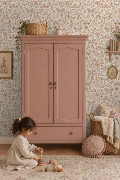 Kinderspielzimmer mit einem Kleiderschrank vor einer floralen Tapete mit Schmetterlingsmotiven und einem spielenden Kind.