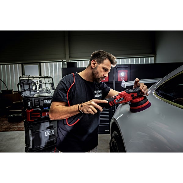 Ein Handwerker poliert den Kotflügel eines Autos mit einer elektrischen Poliermaschine von Flex in einer professionell eingerichteten Werkstatt.