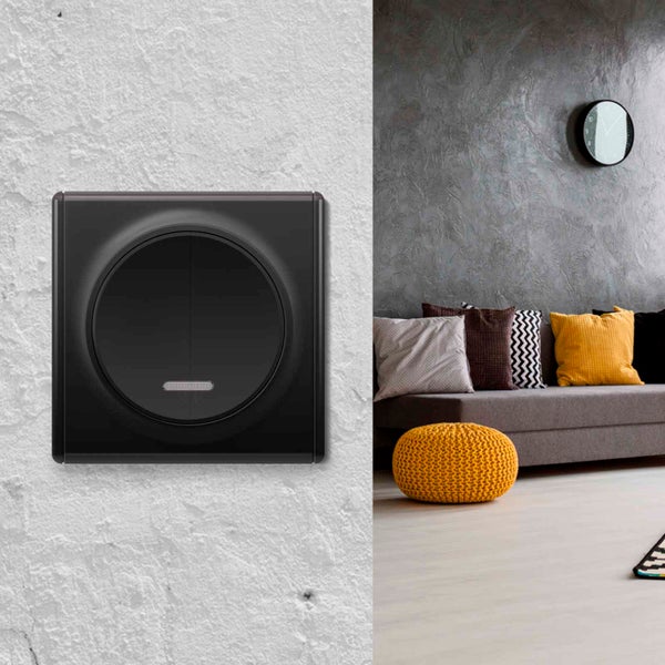 Ein moderner Lichtschalter mit rundem Design auf einer strukturierten Wand, daneben ein Ausschnitt eines Wohnzimmers mit Sofa und Dekoration.