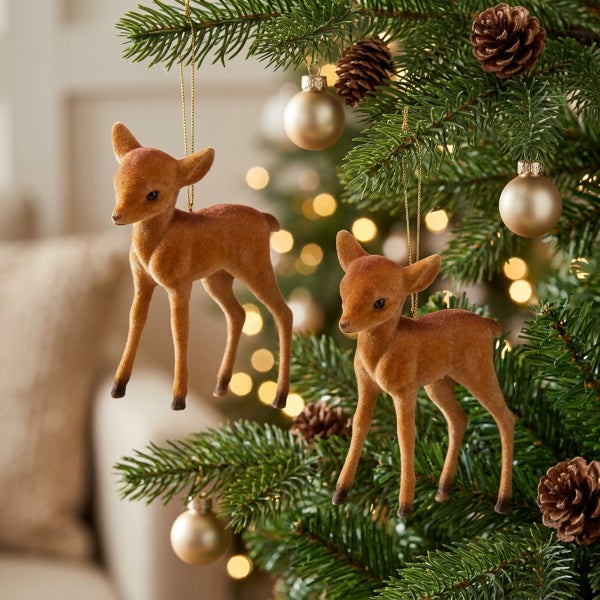 Zwei Reh Anhänger als Baumschmuck aus beflocktem Material hängend an einem Weihnachtsbaum mit Tannenzapfen und Kugeln.