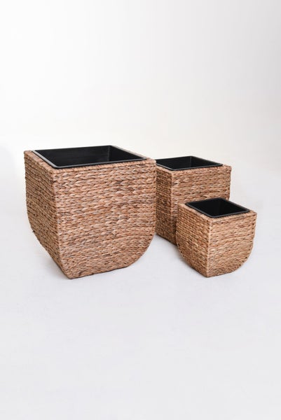 Set aus drei quadratischen Pflanzgefäßen aus geflochtener Wasserhyazinthe mit schwarzem Kunststoffeinsatz in verschiedenen Größen.
