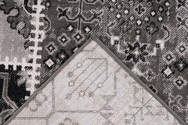 Schwarz-grauer Teppich mit orientalischem Patchwork-Muster, Detailansicht der Oberseite und der textilen Rückseite.