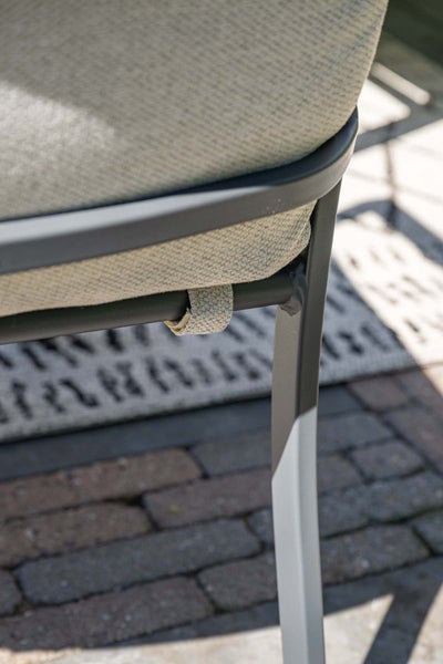 Nahaufnahme eines Gartenstuhls mit Metallrahmen und Textilsitzkissen inklusive Befestigungslasche.