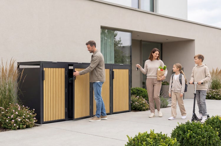 Moderne Mülltonnenbox für vier Tonnen mit Holzlamellen vor einem Haus, während ein Mann eine Tür öffnet und eine Familie ankommt.