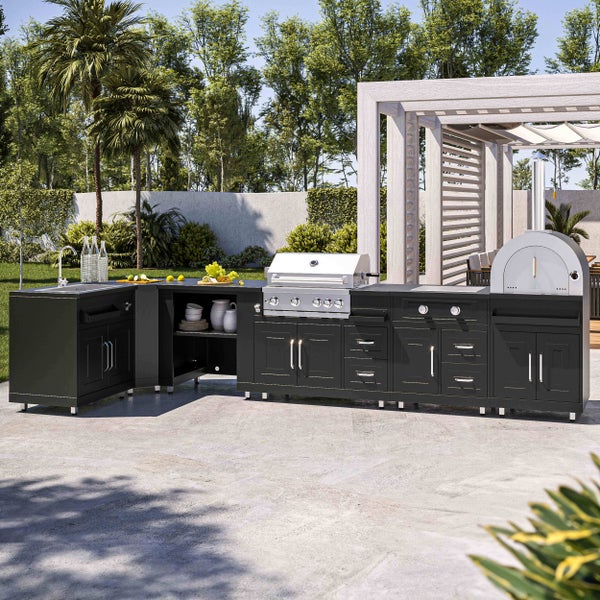 Moderne Außenküche mit dunkelgrauen Schränken, Edelstahl-Gasgrill, Pizzaofen und Spülbecken auf einer Steinterrasse in einem hellen Garten.