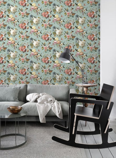Vliestapete mit Blumenmuster in einem modernen Wohnzimmer mit grauem Sofa und schwarzem Schaukelstuhl.