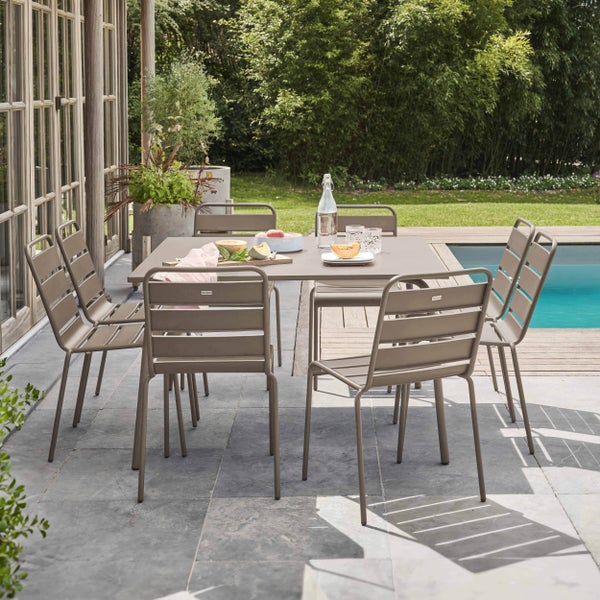 Modernes Gartenmöbel-Set aus Metall mit einem rechteckigen Tisch und sechs Stapelstühlen auf einer Steinterrasse am Pool.