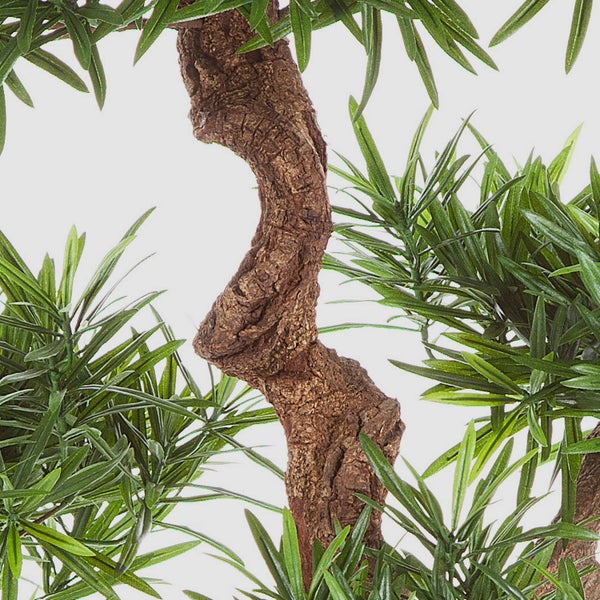 Nahaufnahme eines künstlichen Bonsai Baums mit strukturierter Rinde und grünen Nadeln.