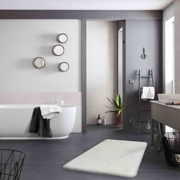 Helles Badezimmer mit Badewanne, Spiegeln, Handtuchhalter und Badteppich