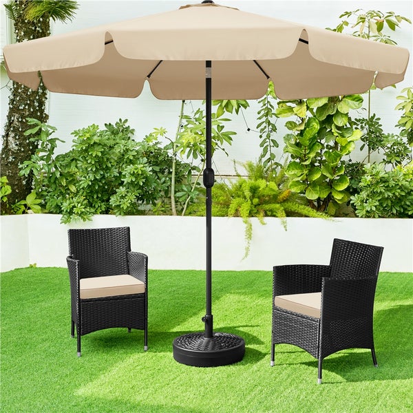 Gartenszene mit Sonnenschirm, zwei Rattansesseln und einem Sonnenschirmständer auf einer Rasenfläche