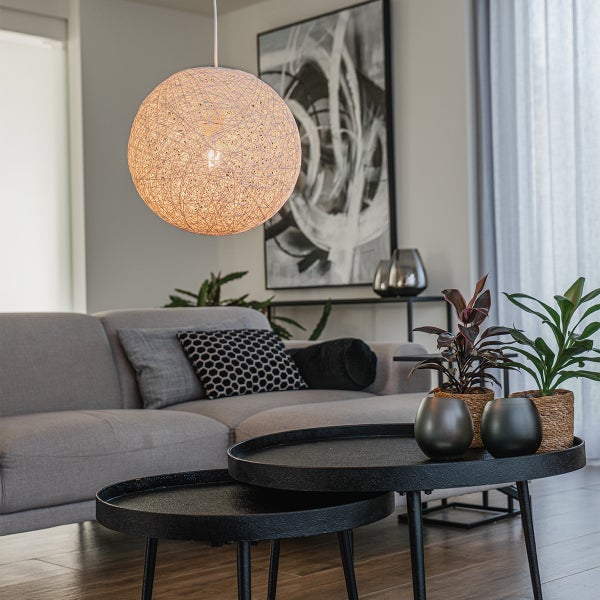 Modernes, helles Wohnzimmer mit runder Pendelleuchte aus Geflecht, grauem Sofa, schwarzen runden Couchtischen und Zimmerpflanzen.