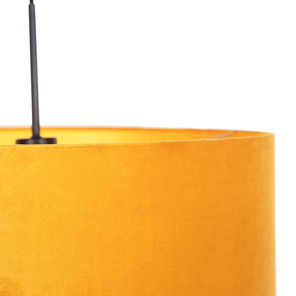 Nahaufnahme eines senfgelben Lampenschirms aus Samt für eine Pendelleuchte mit schwarzer Aufhängung.