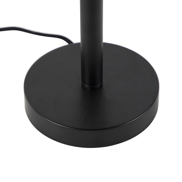 Schwarzer, runder Standfuß einer Tischlampe aus Metall mit Kabel.