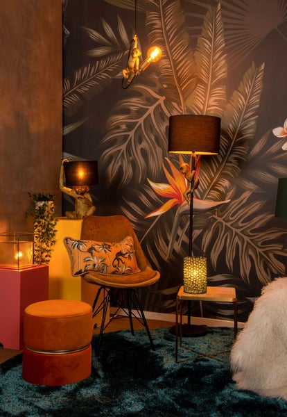 Dekoratives Zimmer mit Dschungeltapete, Sessel, Tisch, Hocker und Lampen mit Affenmotiven.