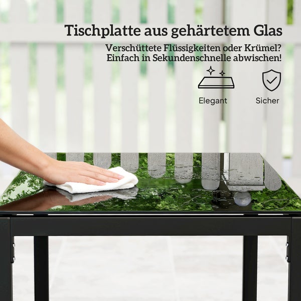 Eine Hand wischt eine Tischplatte aus gehärtetem Glas mit einem Tuch sauber. Symbole für elegant und sicher sind abgebildet.