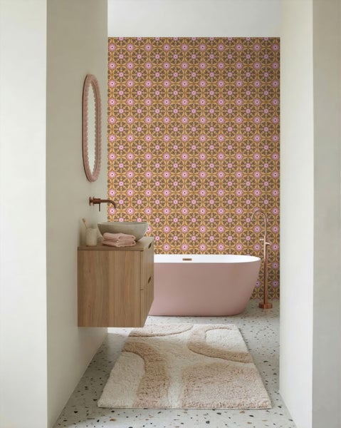 Modernes Badezimmer mit gemusterter Tapete, freistehender Badewanne, hölzernem Waschtisch mit Steinwaschbecken, rundem Spiegel und gemustertem Teppich.