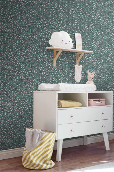Vliestapete mit Leopardenmuster in einem hellen Kinderzimmer mit Wickeltisch, Wandregal und gestreiftem Wäschekorb.