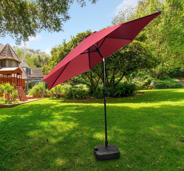 Garten Szene mit einem roten Sonnenschirm auf einem Rasen.