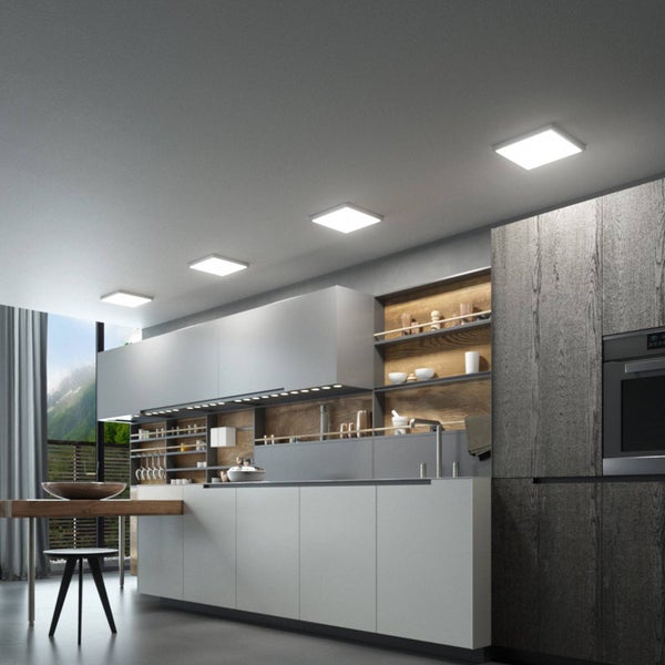 Vier quadratische LED-Deckenpaneele in einer modern eingerichteten Küche mit grauen Fronten, Holzregalen und integrierter Unterbaubeleuchtung.