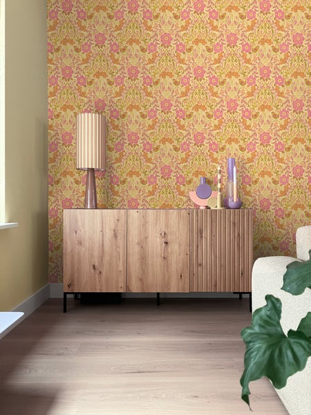 Wohnzimmer mit floral gemusterter Tapete und Holzkommode