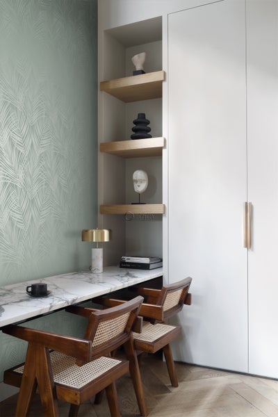 Arbeitsplatz mit Schreibtisch, Stühlen, Regalen und dekorativen Objekten in einem hellen Raum