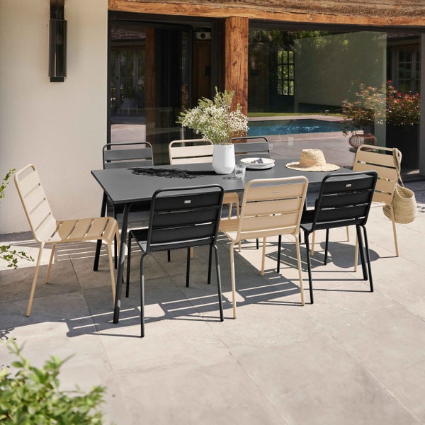 Modernes Gartenset mit rechteckigem Metalltisch und passenden Metallstühlen in Beige und Schwarz auf einer hellen Steinterrasse.