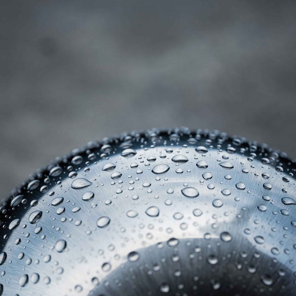Wassertropfen auf einer gebürsteten Metalloberfläche mit wasserabweisendem Effekt.