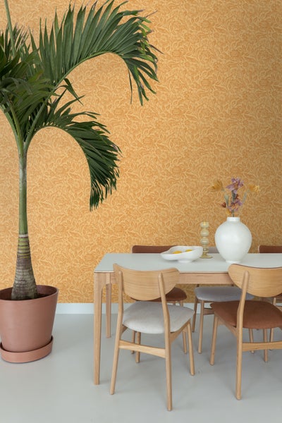 Esszimmer mit Esstisch, Stühlen, Zimmerpflanze und gemusterter Tapete