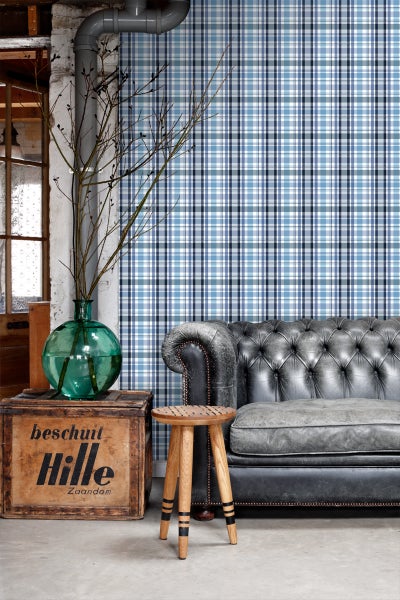 Wohnzimmer mit karierter Tapete, Ledersofa, Holzhocker und Dekoration