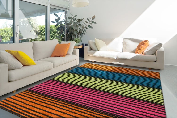 Heller Wohnraum mit zwei Sofas und einem großen, gestreiften Teppich in verschiedenen Mustern und kräftigen Streifen auf dem Boden.
