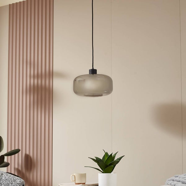 Moderne Pendelleuchte mit ovalem Schirm aus Rauchglas und schwarzem Kabel in einem hellen Raum mit dekorativen Wandpaneelen.