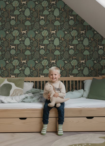 Kinderzimmer mit Vliestapete im Wald-Design mit Bäumen und Hunden, dazu ein helles Holzbett mit grüner Bettwäsche.