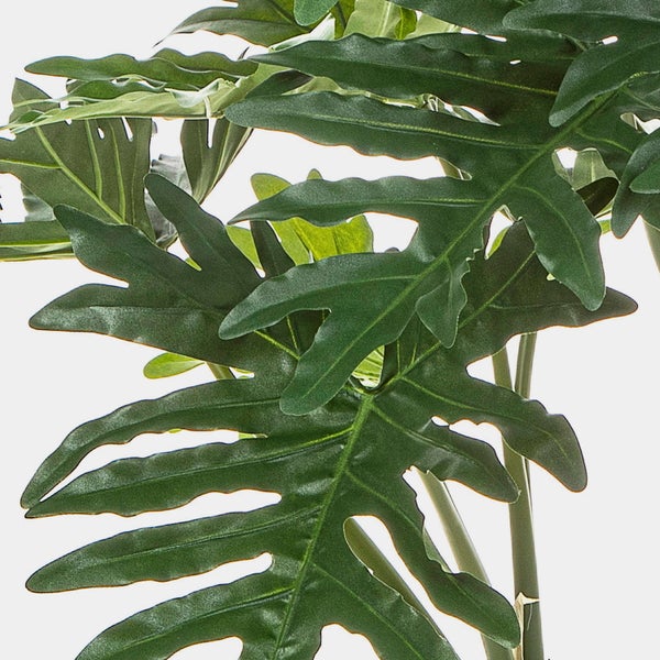 Künstlicher Pflanzenstamm mit Luftwurzeln in einem schwarzen Topf.