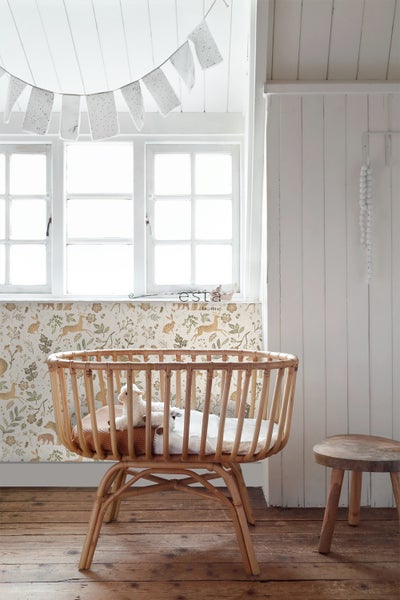 Gemütliches Kinderzimmer mit Gitterbett aus Holz, floraler Tapete und Holzfußboden