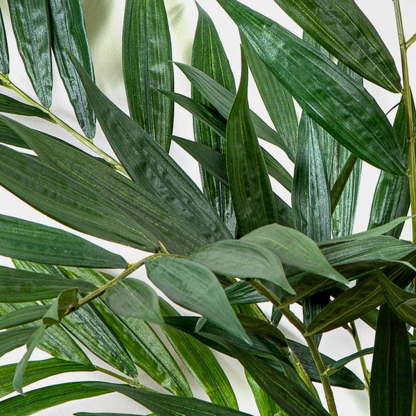 Künstliche Palme mit grünen Blättern und segmentiertem Stiel am Ansatz.