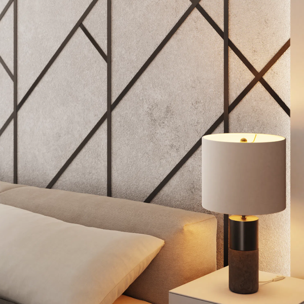 Nachttischlampe auf einem Nachttisch neben einem Bett mit gemustertem Kopfteil