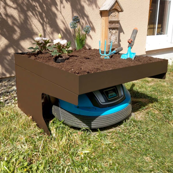 Garten Szene mit Rasenmähroboter unter einem Pflanztisch mit Blumen, Gartengeräten und Insektenhotel