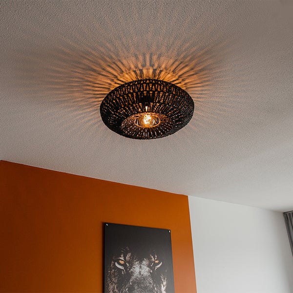 Schwarze Deckenleuchte aus Geflecht mit strahlenförmigem Lichteffekt an der Decke.