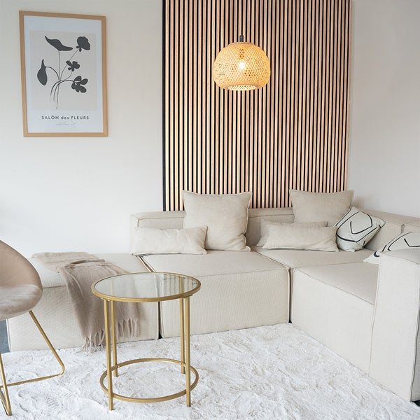 Modernes, helles Wohnzimmer mit modularem Sofa, rundem Glastisch, Holzlamellen-Wandpaneel und einer geflochtenen Hängeleuchte.