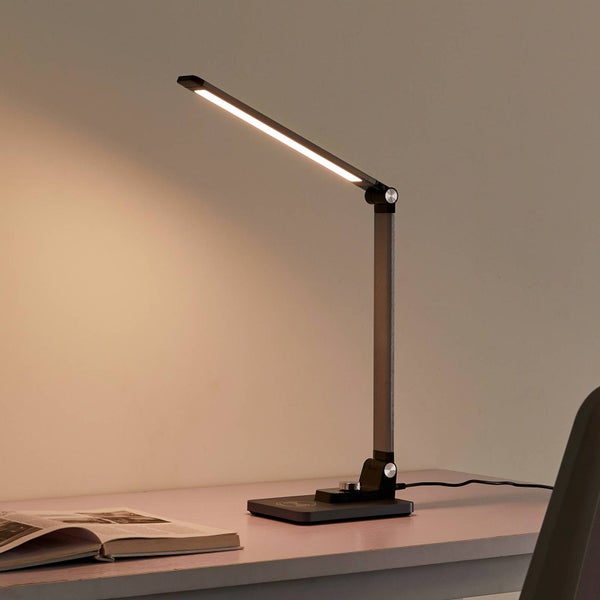 Moderne LED Schreibtischlampe aus Metall mit verstellbarem Arm auf einem Schreibtisch neben einem Buch