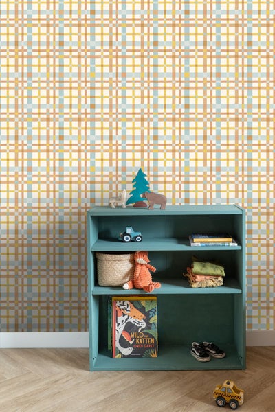 Kinderzimmer mit Tapete im mehrfarbigen Karomuster. Vor der Wand steht ein petrolblaues offenes Regal mit Spielzeug und Büchern auf hellem Parkettboden.