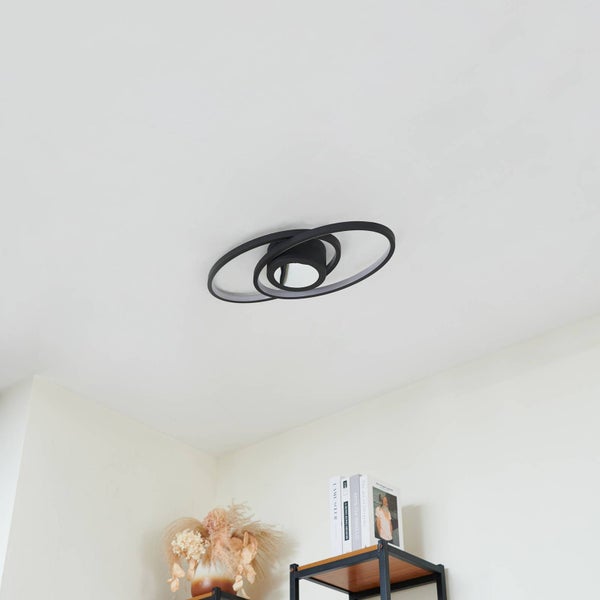 Moderne schwarze LED-Deckenleuchte mit überlappenden ovalen Ringen an einer weißen Decke in einem hellen Zimmer.