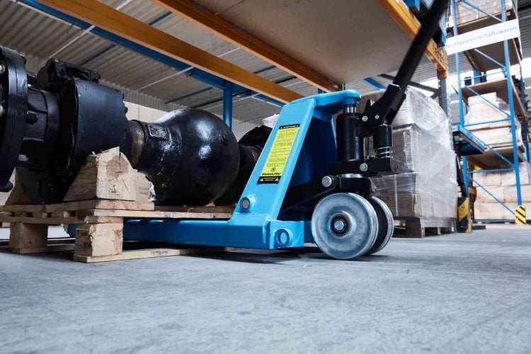 Blauer Hubwagen von HanseLifter transportiert ein schweres Maschinenteil auf einer Palette in einem Lager.